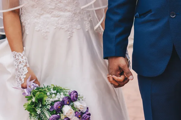Bride and groom holding hands with a bridal bouquet at a church wedding
